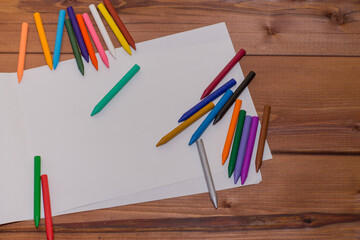 Obraz premium Colorful crayons with a white blank sheet of paper on a wooden background