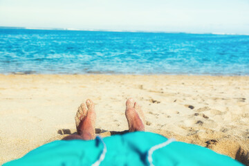 Man enjoying at the beach - focus is on feet.