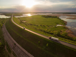 beautiful landscape with a ride on the highway the trucks and a few cars at sunset. aerial view