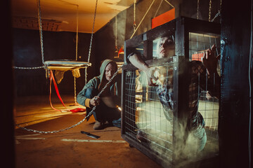 Bloody maniac and his female victim in the cage.