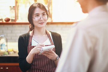 women barista coffee list order from customer with blurry background - female small business owner coffee shop