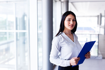 Attractive woman standing in business building with paper board in her hands