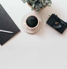 coffee cup, Retro camera, notebook, white pen and Plastic plants on white table is background with space for text, top view