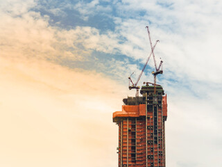 Construction site with cranes on a building blue sky and sunset is background