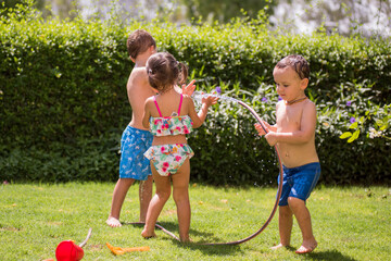 Children playing with water in the garden at the sunny day