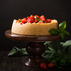 Dark photo of delicious homemade strawberry cheesecake decorated with basil leaves on old wooden background. Selective focus.