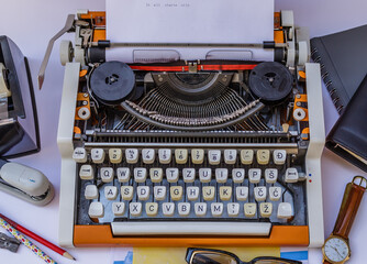 Old typewriter on a white background with a lot of items around and typed words " It all starts with "
