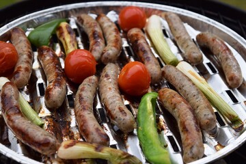 Grilling sausages and vegetables and spices on the grill