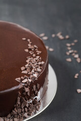 Mousse cake with mirror glaze decorated chocolate chips on a dark background