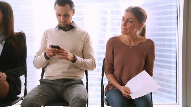 Business people group sitting in row on chairs, three job applicants await for their turn in queue, waiting for job interview concept, man and two women preparing for audition, feeling stressed bored