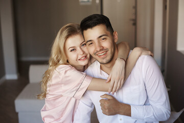 Young romantic couple at home. Caucasian blonde woman and brunette man. Lovers hugging in living room.