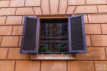 Detail of a wooden window with decorative black iron and shutters open