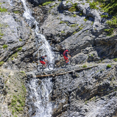 Mountainbiker durchqueren Gebirgsbach mit Wasserfall