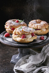 Homemade choux pastry cake Paris Brest with raspberries, almond and rosemary, served on black...