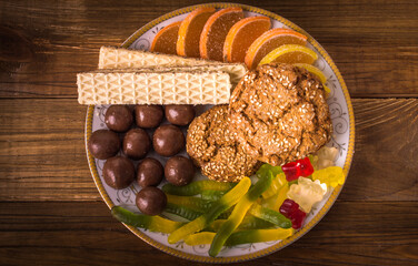 Sweets. Different sweets in a plate on a wooden background