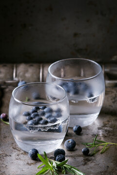 Tonic water cocktail with rosemary, blueberries. Two cold glasses over over dark texture metal background. Refreshing beverage alco non alcohol
