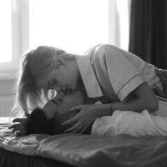 Young romantic couple relaxing and kissing in bed. Pretty beautiful blonde girl and brunette man. Black and white photo.
