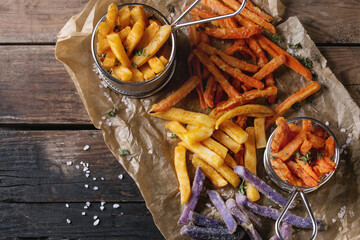 Variety of french fries traditional potatoes, purple potato, carrot served with salt, thyme on...