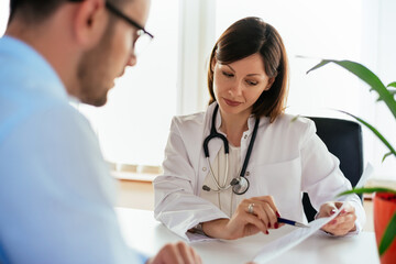 Doctor talking to her male patient at office, showing results