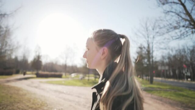 Gimbal shot of female teen girl walking in town park in spring sunny day, uhd prores footage