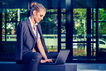 Young attractive business woman using laptop in an urban setting. Business concept