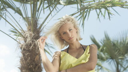 Fototapeta premium Young beautiful caucasian girl posing over tropical palm trees. 