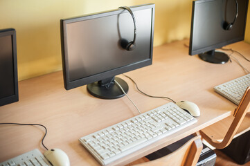 Row of computers with headphones on desk in primary school