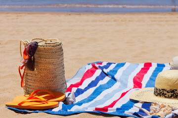 beach towel and sunbathing accessories on sandy beach by the sea close up