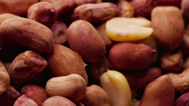 Spinning pile of roasted peanuts in dark red skins.