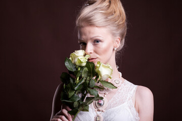 Gorgeous blonde woman in victorian dress with roses in hands. Rich and vintage. Luxury and elegance. Studio photo