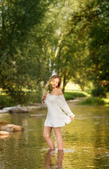 Young woman in the white dress in the middle of a creek..