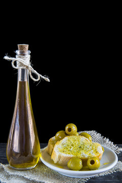 Aceite de oliva virgen extra y rebanadas de pan con aceitunas verdes