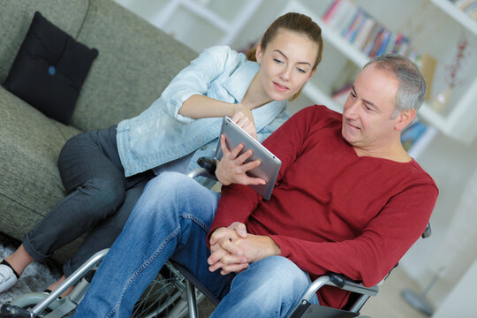 Young lady showing tablet screen to disabled man