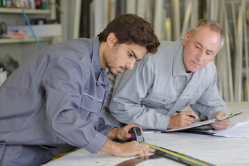Man using tape measure, older man watching