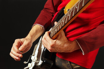 Rock guitarist put fingers for chords on electric guitar on the black background