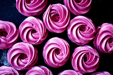 Many purple marshmallow on a dark surface. A contrasting picture.A work of culinary art