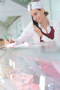 Woman at meat counter taking telephone order