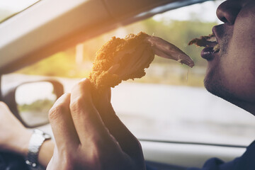 Business man driving car while eating fried chicken dangerously