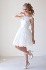 girl in a wedding dress stands in a white room wedding