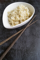 Japanese sushi with chopsticks over a bowl of soy sauce, brown rice and chukka salad on a black background. Top view with copy space.