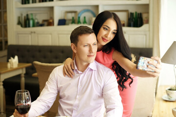 Young romantic beautiful caucasian couple having good time and making selfie in restaurant