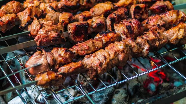 Meat grilled on skewers over the glowing. Tasty food for barbecue party. Roasted grill meat with crust. Close up of pork meat prepared on fire glow. Cooked shashlik or shish kebab