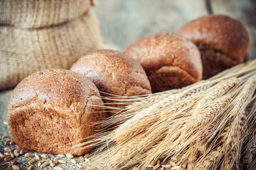 Fresh bread buns, wheat ears and sack of flour.