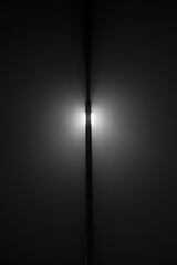 Abstract minimalistic black and white photo of a street lamp on a foggy night