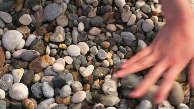 woman's hands touching sea pebble, close-up shot