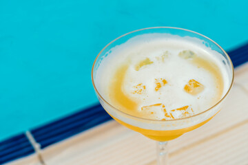 glass of pina colada by the swimming pool