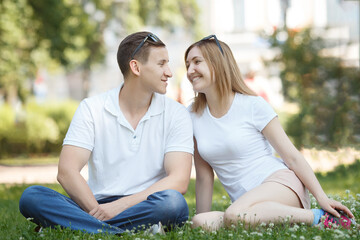 Young couple having fun outdoors in the park, smiling at each other