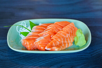 Salmon raw sashimi on green Japanese traditional dish on black table