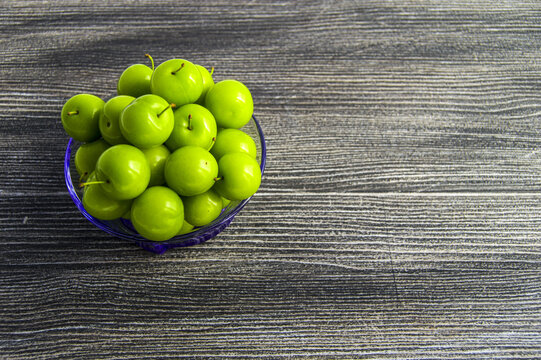 Green sour plums in the plate, plum pictures on the white ground,
Quality and natural life-giving green sour plums

