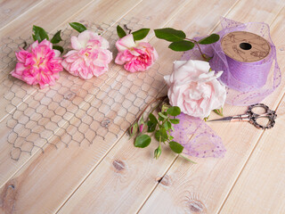 Roses on chicken wire with sequin ribbon and scissors on wooden background